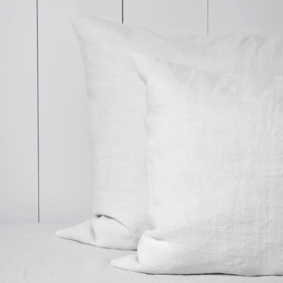 Twee witte linnen kussenslopen op een bed.