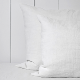 Twee witte linnen kussenslopen op een bed.
