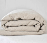 Duurzaam opgevouwen dekbedovertrek van gewassen linnen in de originele, ongeverfde vlaskleur naturel met een off-white streepje.